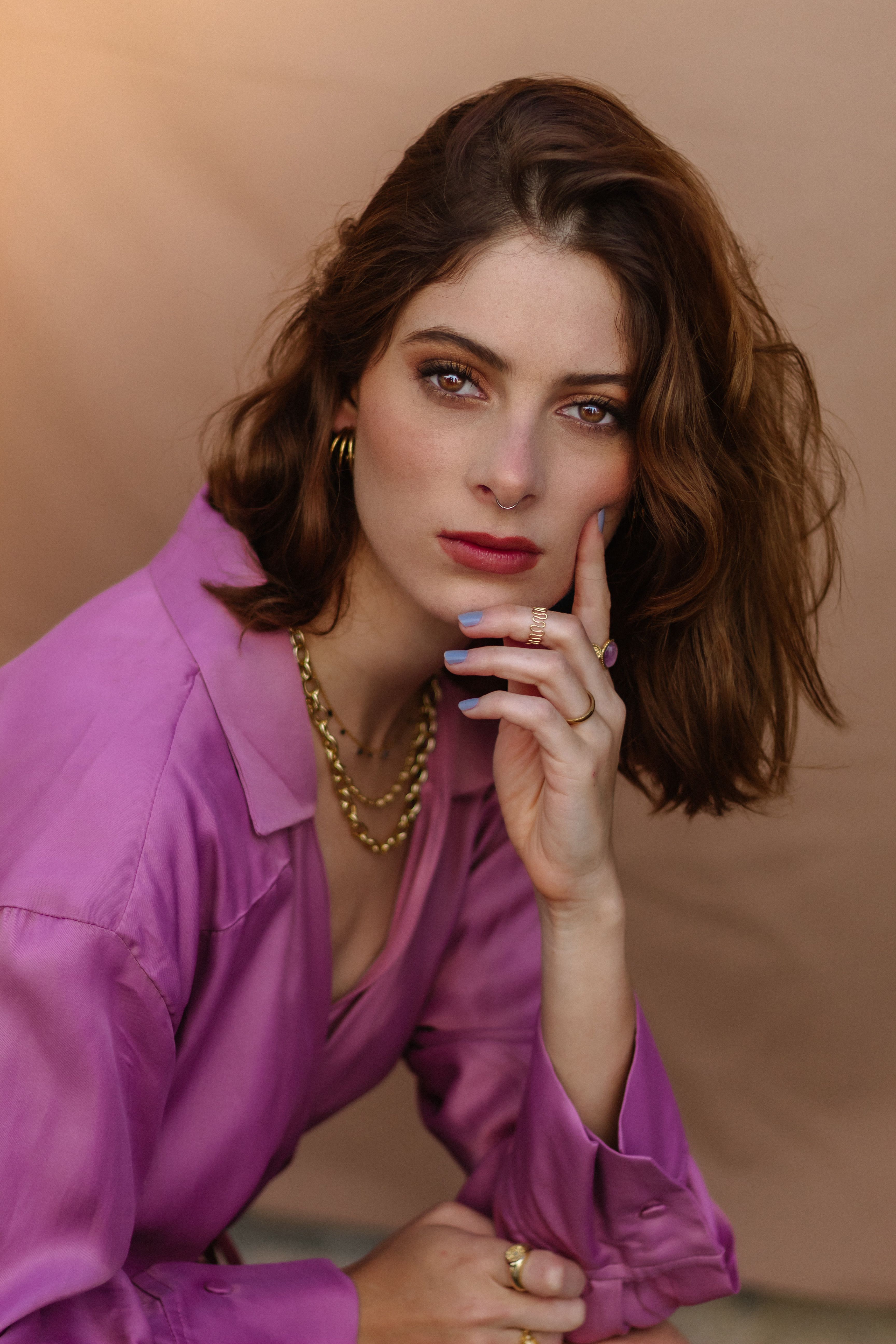 Close-up portrait of a young woman with elegant jewelry, wearing a pink shirt.