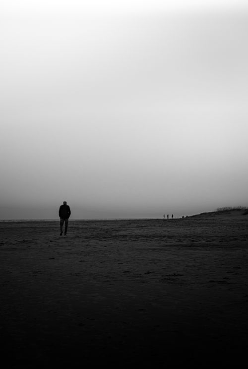 Free A lone person walks on a misty beach, creating a serene and contemplative scene. Stock Photo