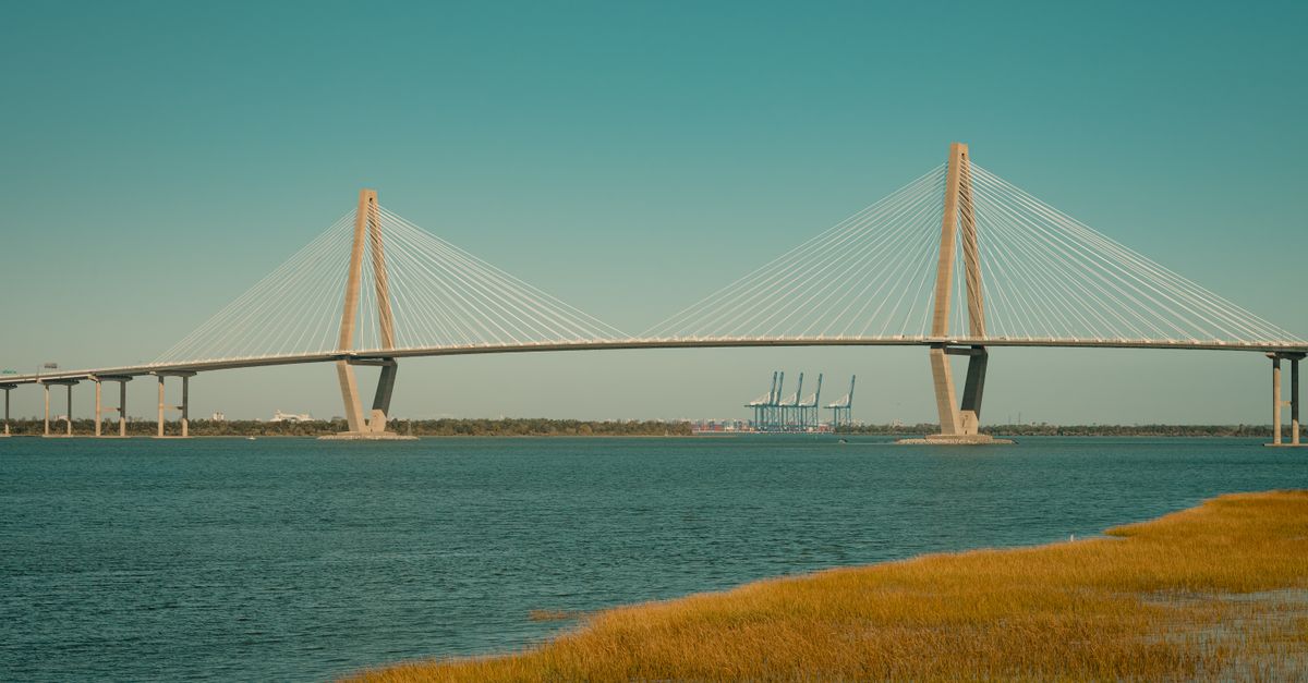 A picturesque view of the Arthur Ravenel Jr. Bridge spanning across a serene river under a clear sky.