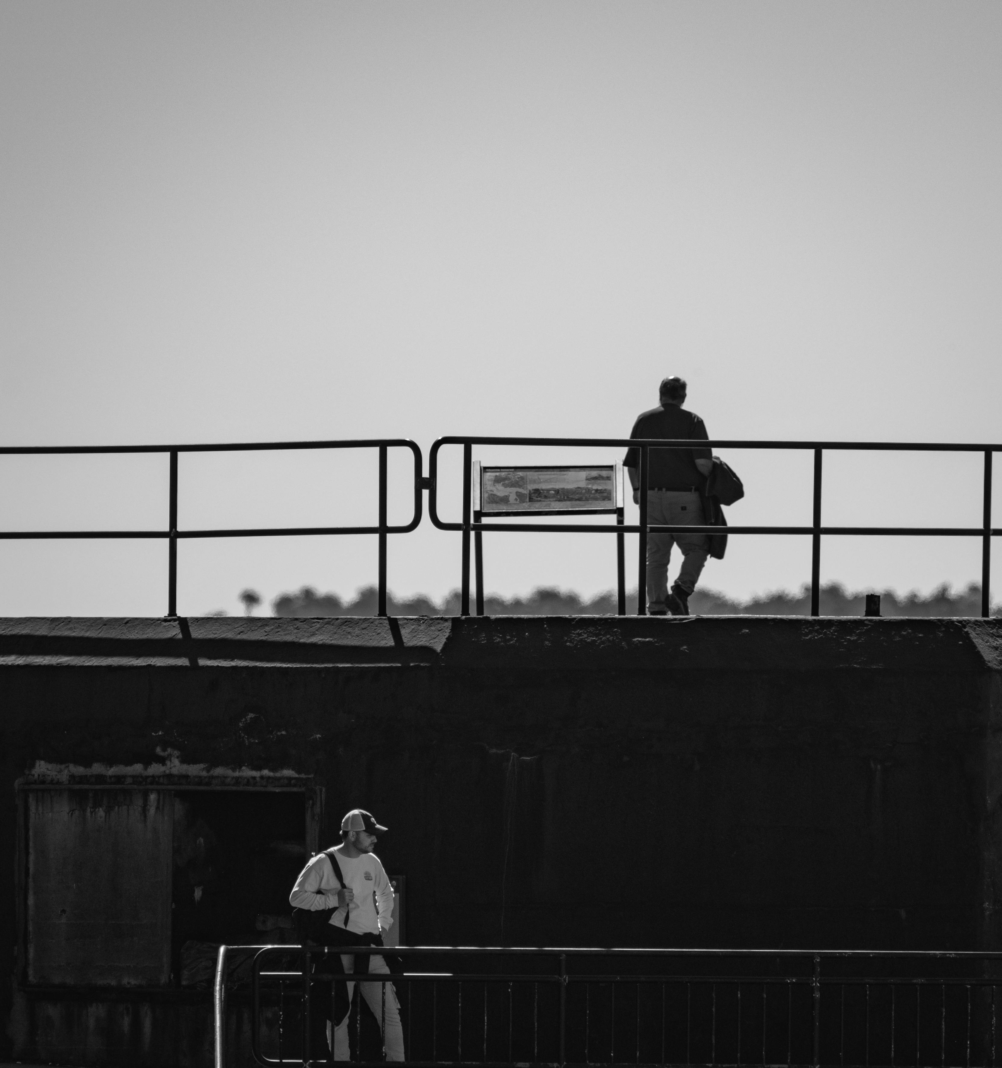 Free Black and white photo depicting two people on an urban bridge, offering a dramatic and moody atmosphere. Stock Photo