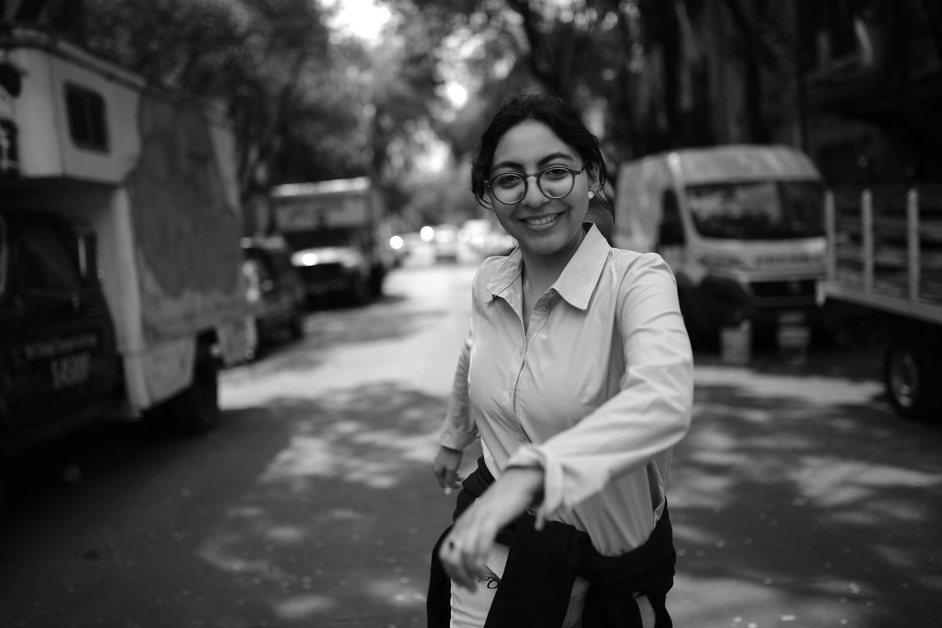 Smiling woman in casual attire walking in a Mexico City street, captured in black and white.