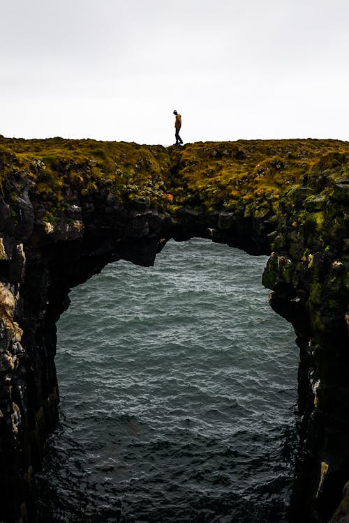 Fotografi Seseorang Berdiri Di Tebing
