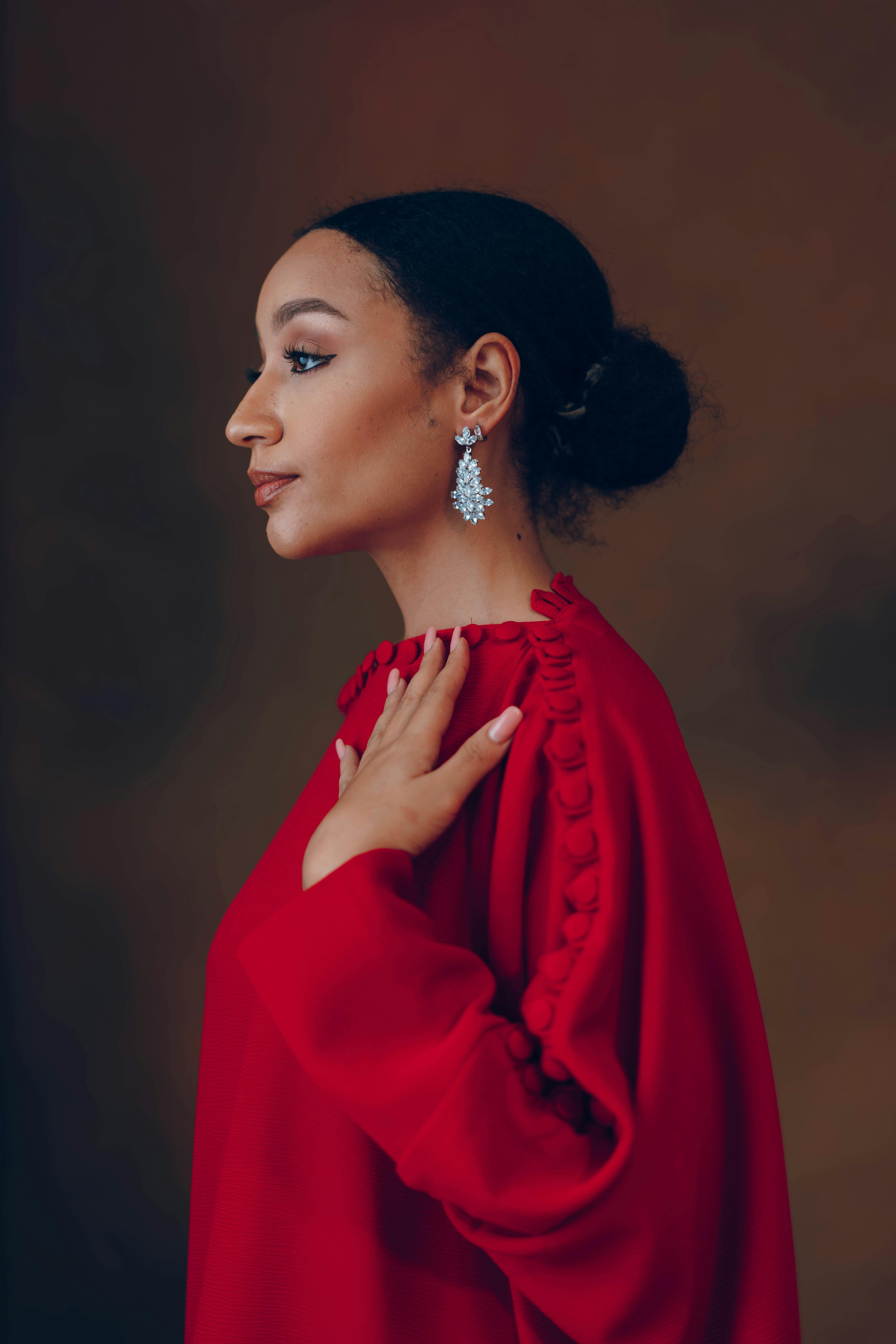 Elegant side profile portrait of an African woman in a red dress with earrings.