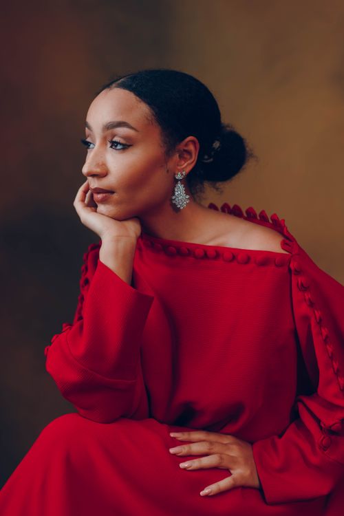 Free A thoughtful African woman in a sophisticated red dress looks to the side, exuding elegance. Stock Photo