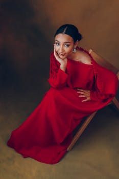 Stylish woman in a red dress seated on a chair, exuding elegance and grace.