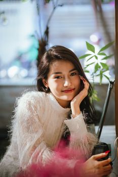Smiling young woman in a cozy sweater with soft lighting in Vietnam.