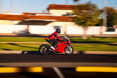 Free Motorcyclist in red jacket riding fast on a city street during daytime. Stock Photo