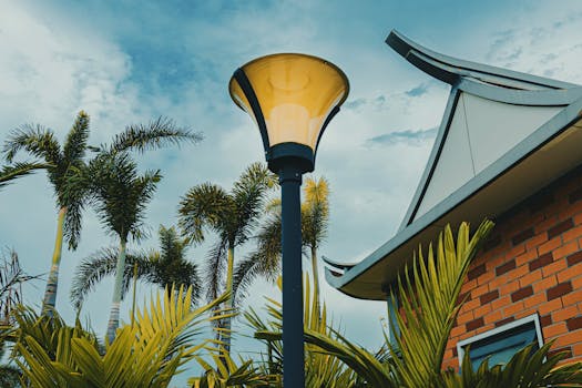 A lamp post amid palm trees and Asian architectural elements under a blue sky.
