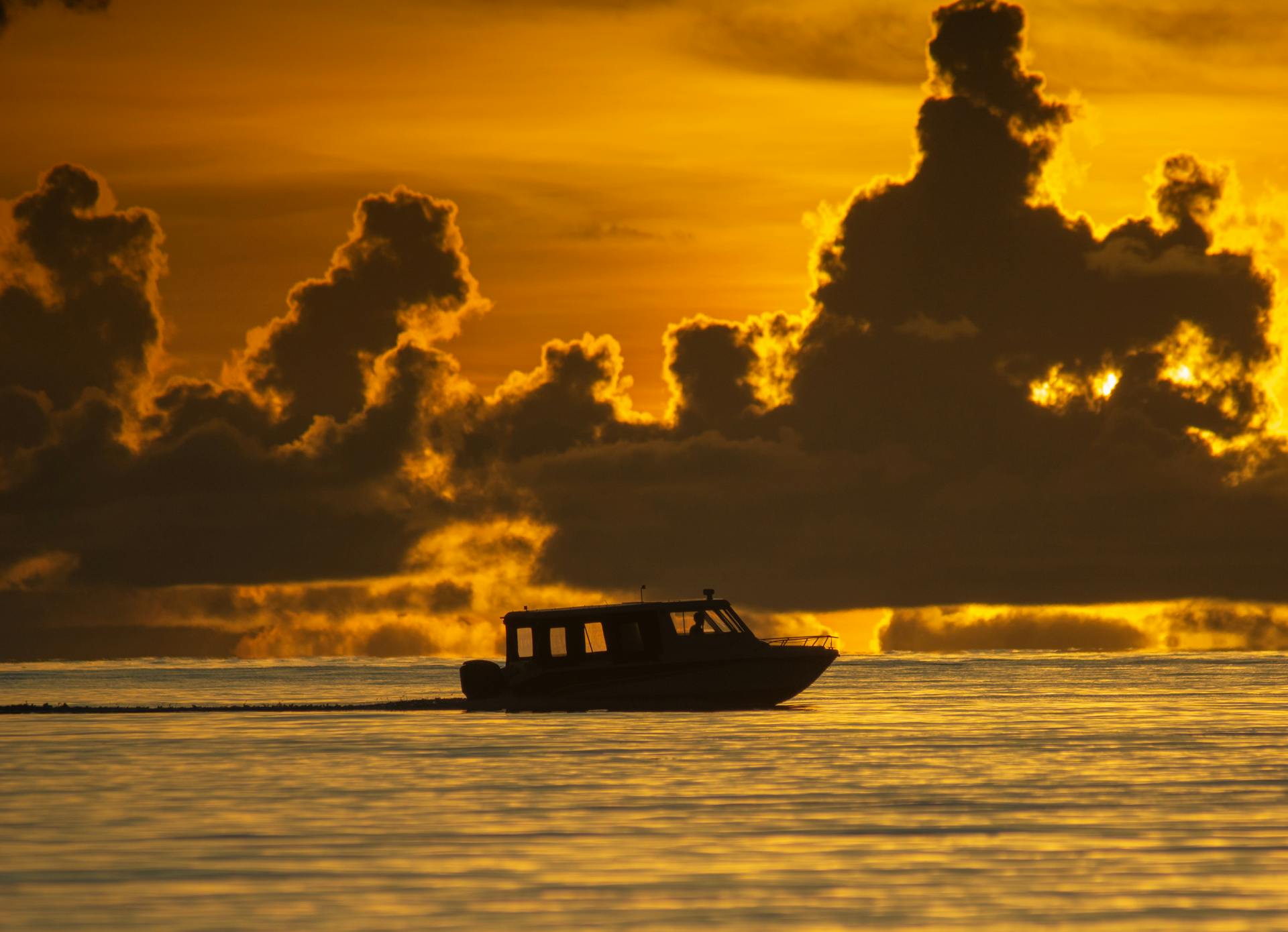 A speedboat glides across the ocean against a dramatic Sri Lankan sunset, silhouetted by vibrant sky.
