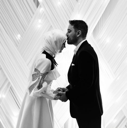Free A tender moment between a couple in elegant attire, captured in black and white. Stock Photo
