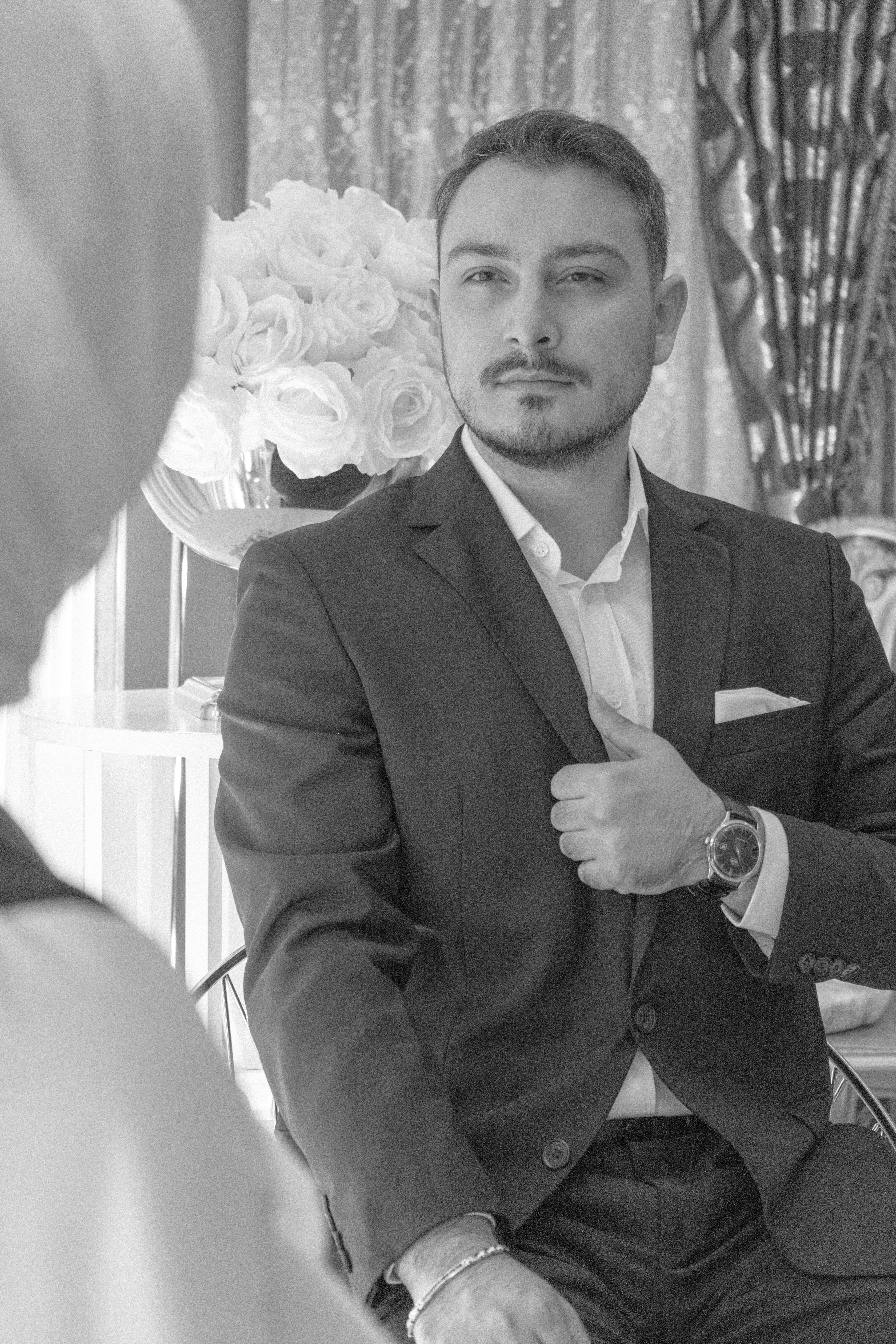 Black and white portrait of a man in a suit, set indoors with elegant decor.