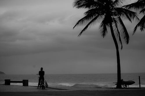 Monochrome Photo of Person Standing on Seashore