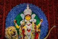 Colorful Durga idol with intricate ornaments and lion at a religious festival.