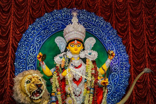 Colorful Durga idol with intricate ornaments and lion at a religious festival.