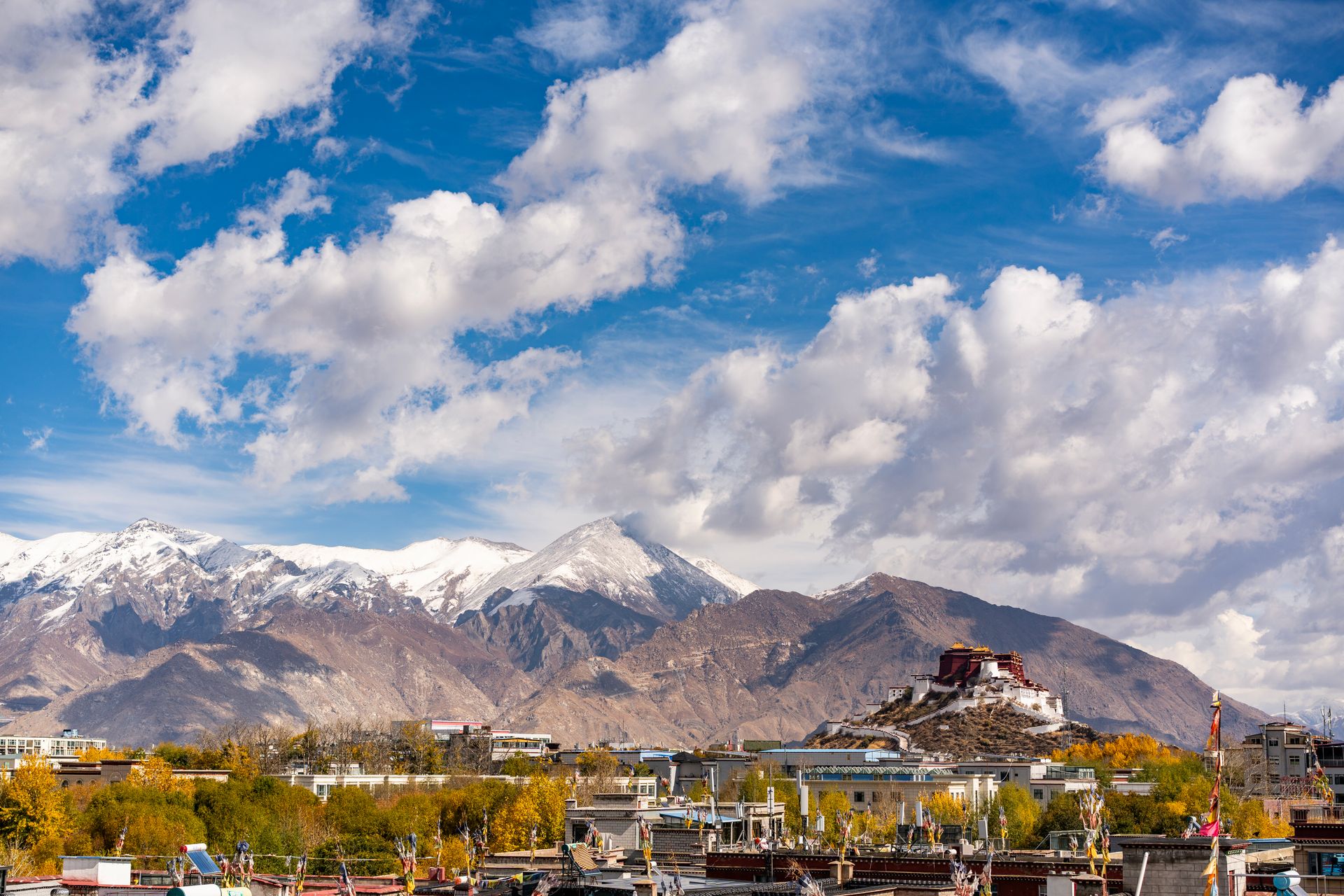 Breathtaking view of Potala Palace amidst mountains and vibrant autumn landscape in Lhasa, Tibet.