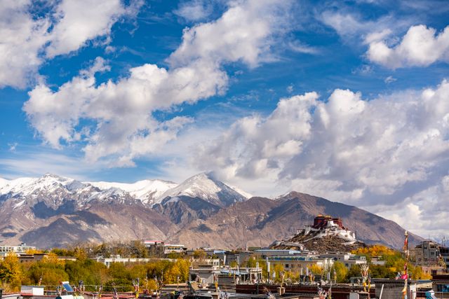 Breathtaking view of Potala Palace amidst mountains and vibrant autumn landscape in Lhasa, Tibet.