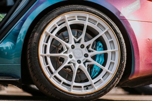 Detailed shot of a white alloy wheel on a stylish car with blue brake caliper.