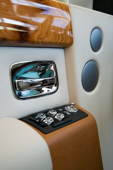 Close-up of luxury car interior features including wood trim and control panel.