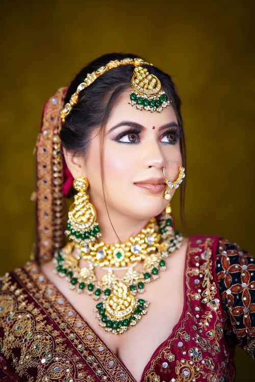 Free Beautiful Indian bride adorned in traditional attire and intricate jewelry, looking off to the side. Stock Photo