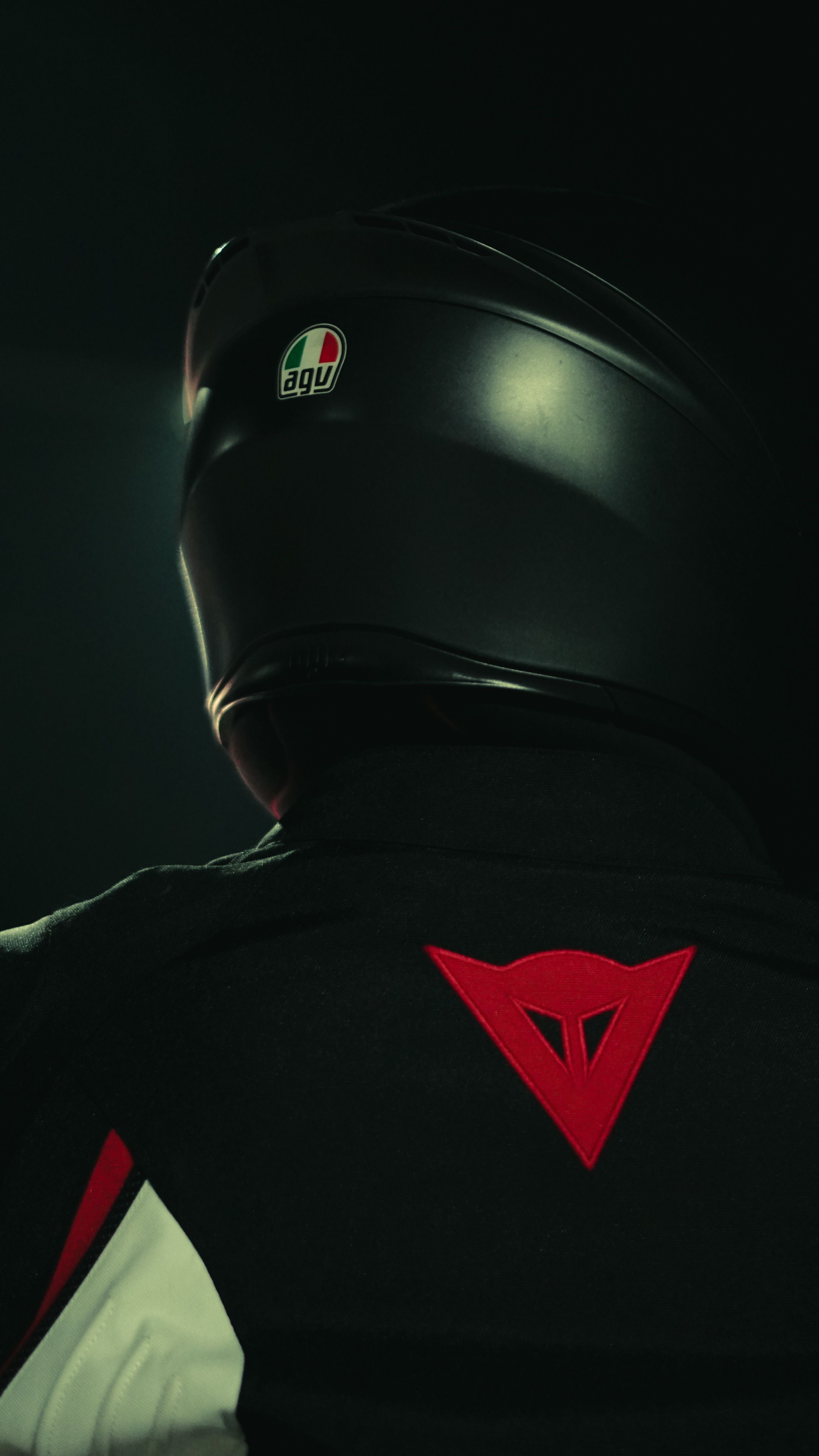 A motorcyclist wearing a helmet and jacket, captured in low light.