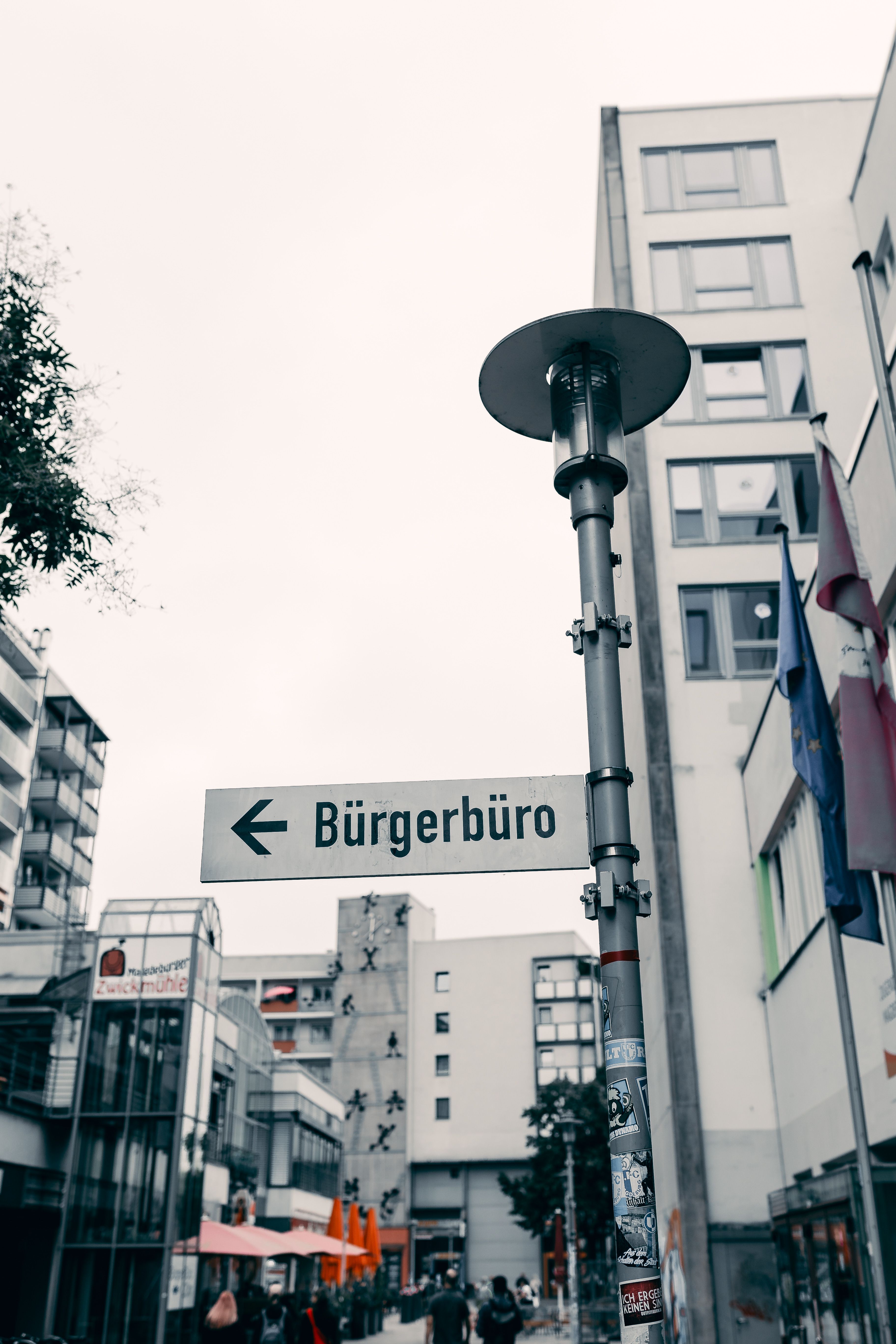 City street with Bürgerbüro sign and modern architecture on an overcast day.