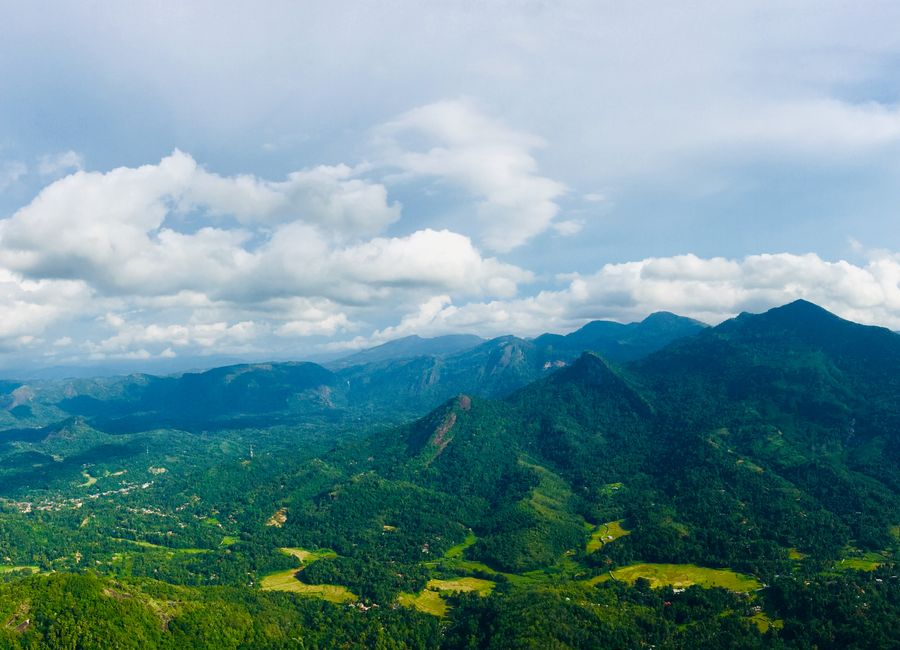 An expansive view of verdant mountains and valleys under a bright sky in Kegalle, Sri Lanka.