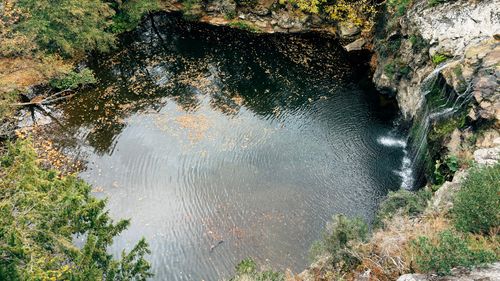 Free A high-angle view of a tranquil pond and waterfall surrounded by autumn foliage, creating a serene natural landscape. Stock Photo