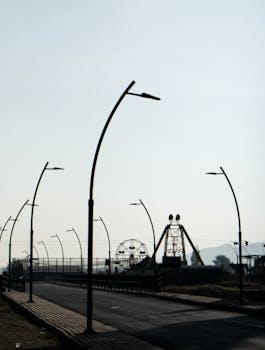 A desolate amusement park with curved street lamps under a clear morning sky.