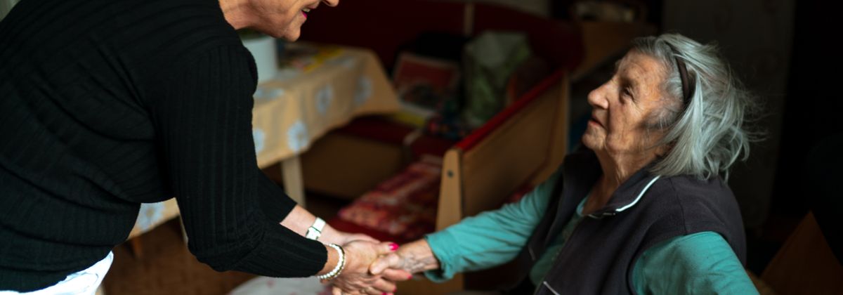 A caregiver holding hands with an older woman