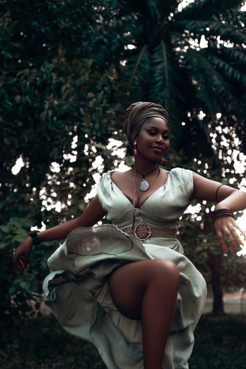 Free Elegant woman in a stylish green dress dancing gracefully in a lush outdoor setting. Stock Photo
