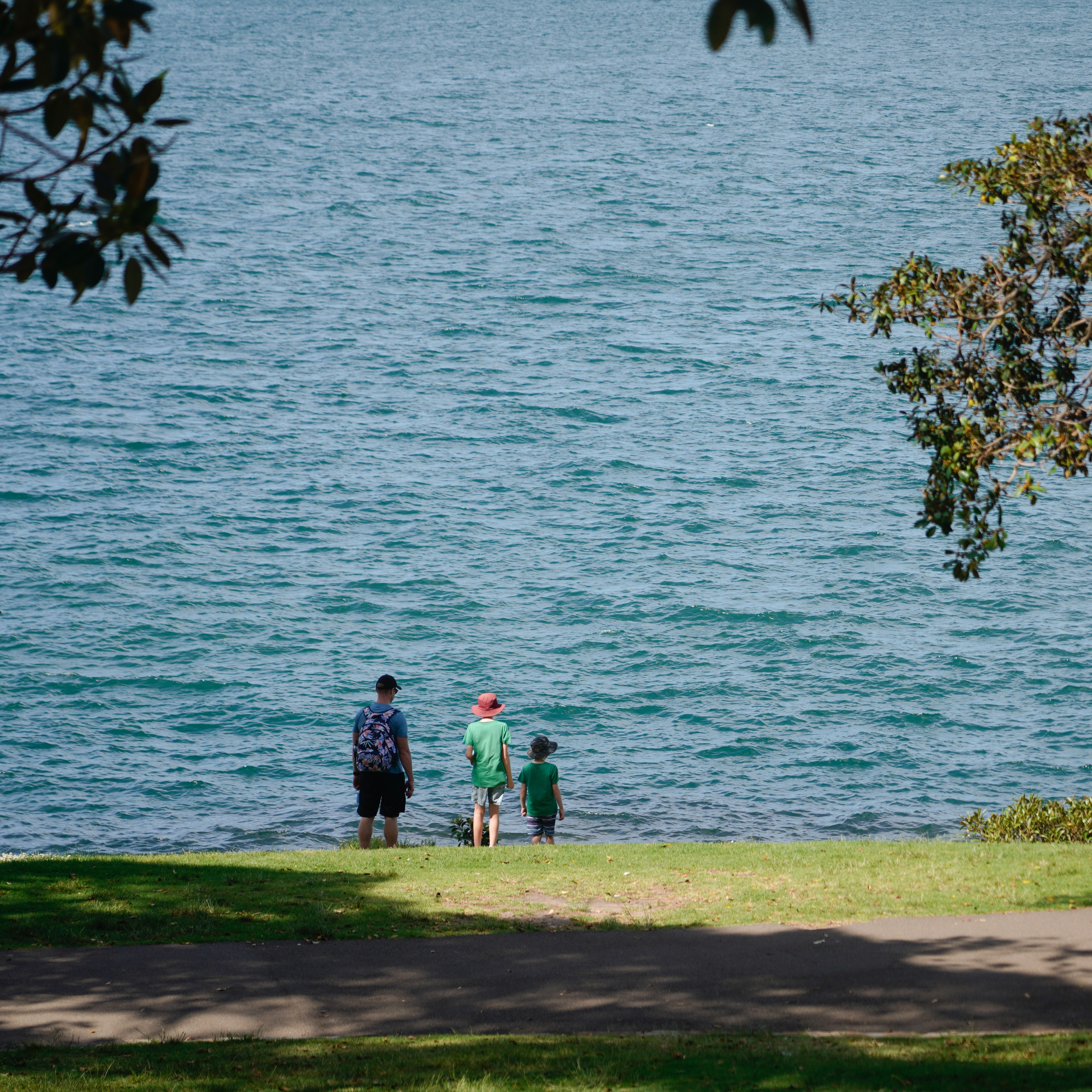 A family enjoying a peaceful walk by the lake on a sunny summer day.