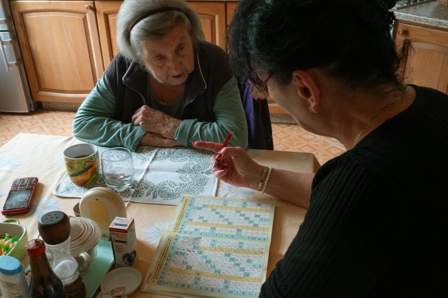 Senior woman and caregiver work together on activity in kitchen