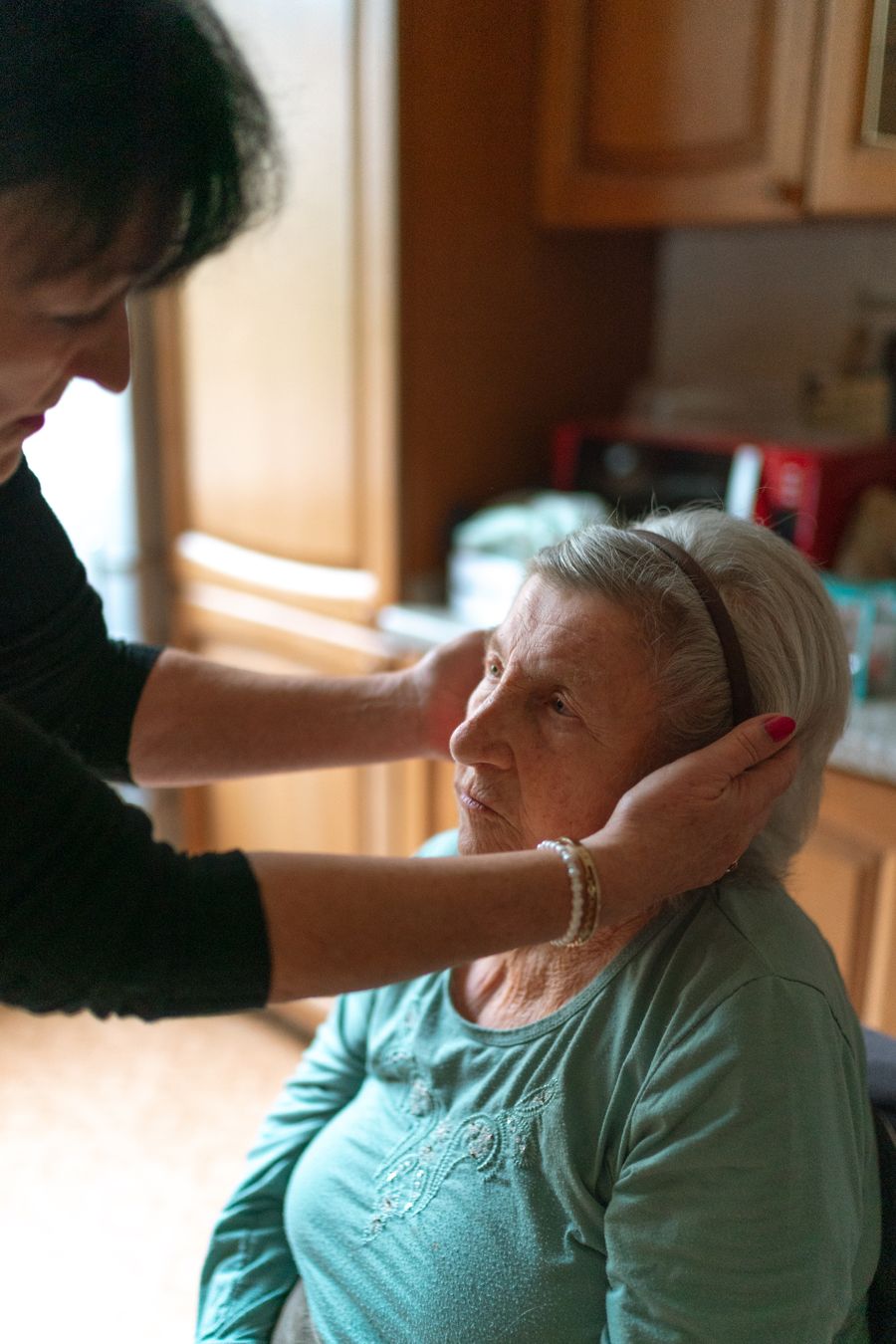 A caregiver warmly assisting a senior woman receiving home care