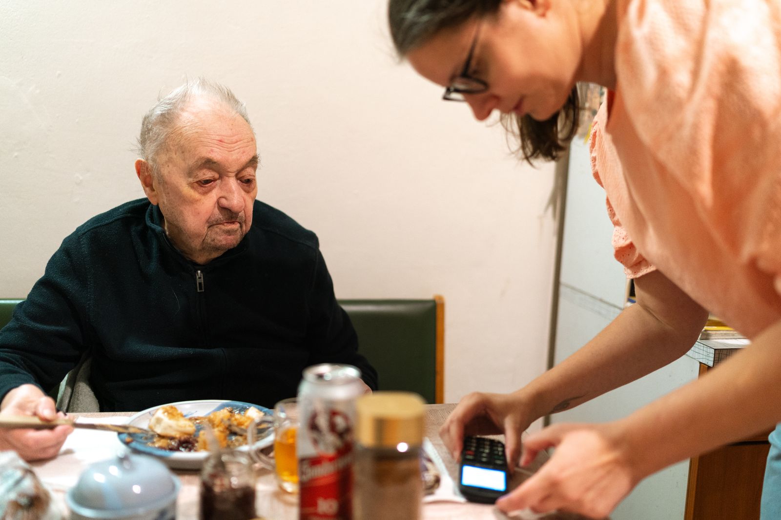 Caregiver assisting an elderly man at mealtime