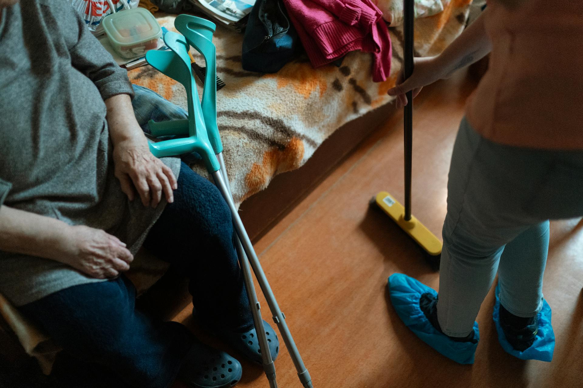 Caregiver helps an elderly woman with cleaning tasks, showcasing home care support.