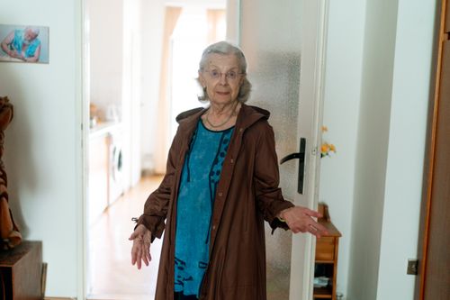 Free Elderly woman standing in a doorway, inside a home in Prague, showcasing daily life. Stock Photo