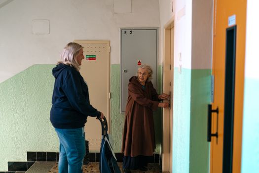 Seniorka a asistentka v chodbě budovy