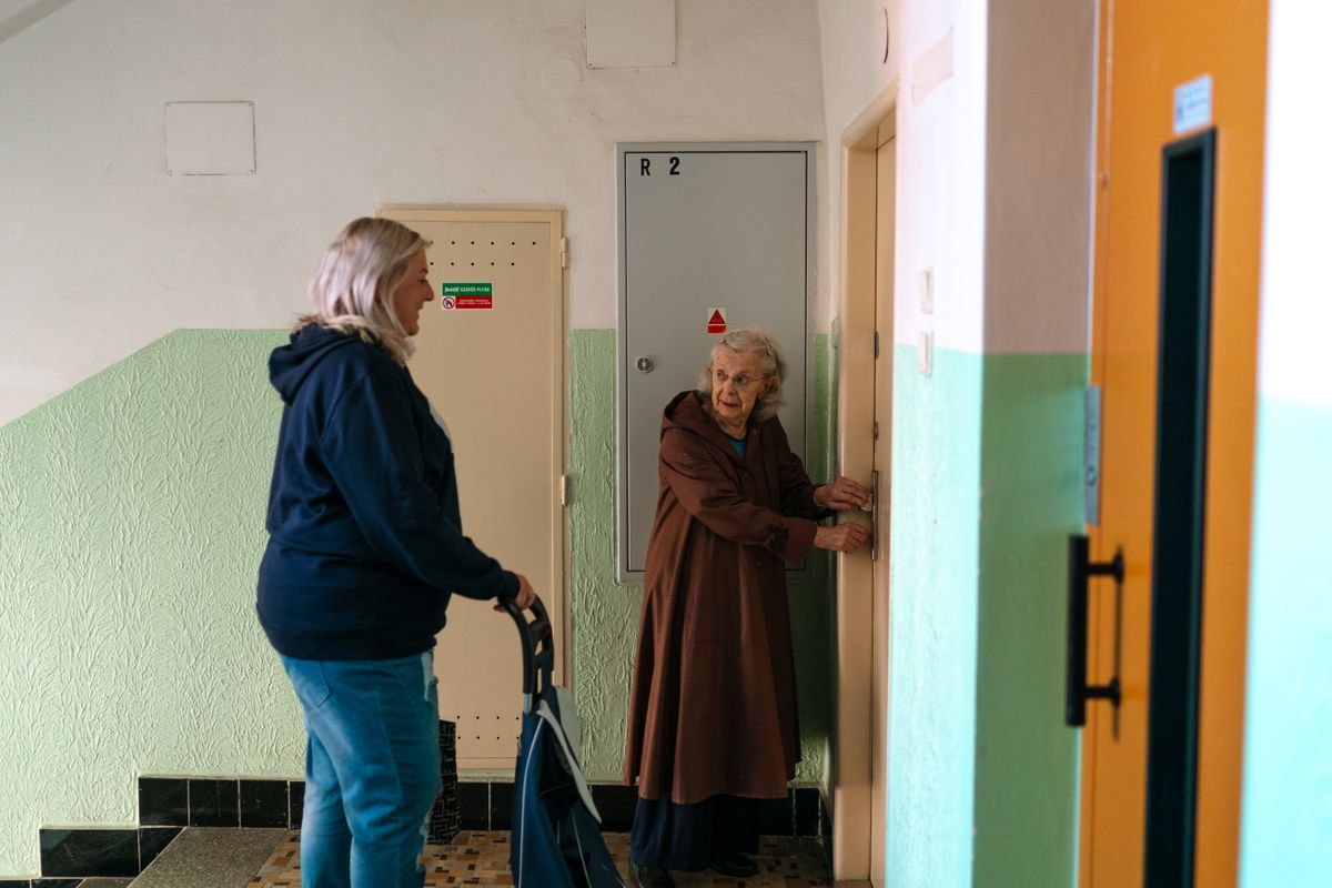 Seniorka a asistentka v chodbě budovy
