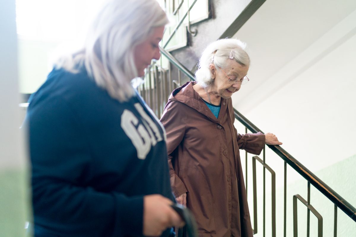 Caregiver assisting an older adult on a staircase