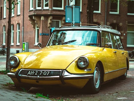 A classic yellow Citroën DS parked in an urban Amsterdam street on a summer day.