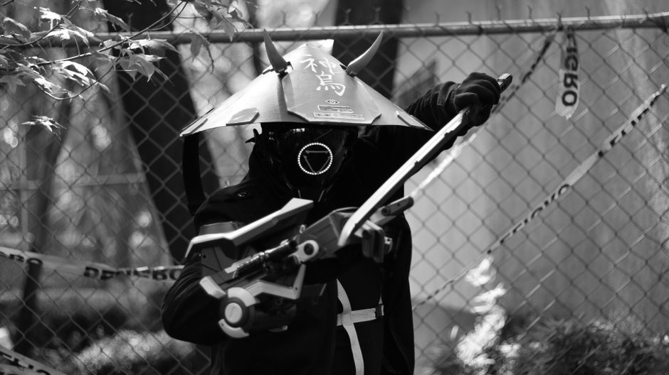 A striking black and white photo of a futuristic samurai warrior holding a weapon, wearing a helmet with Japanese text.