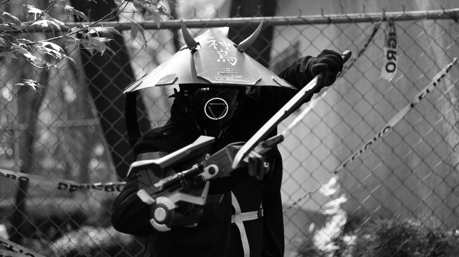 A striking black and white photo of a futuristic samurai warrior holding a weapon, wearing a helmet with Japanese text.