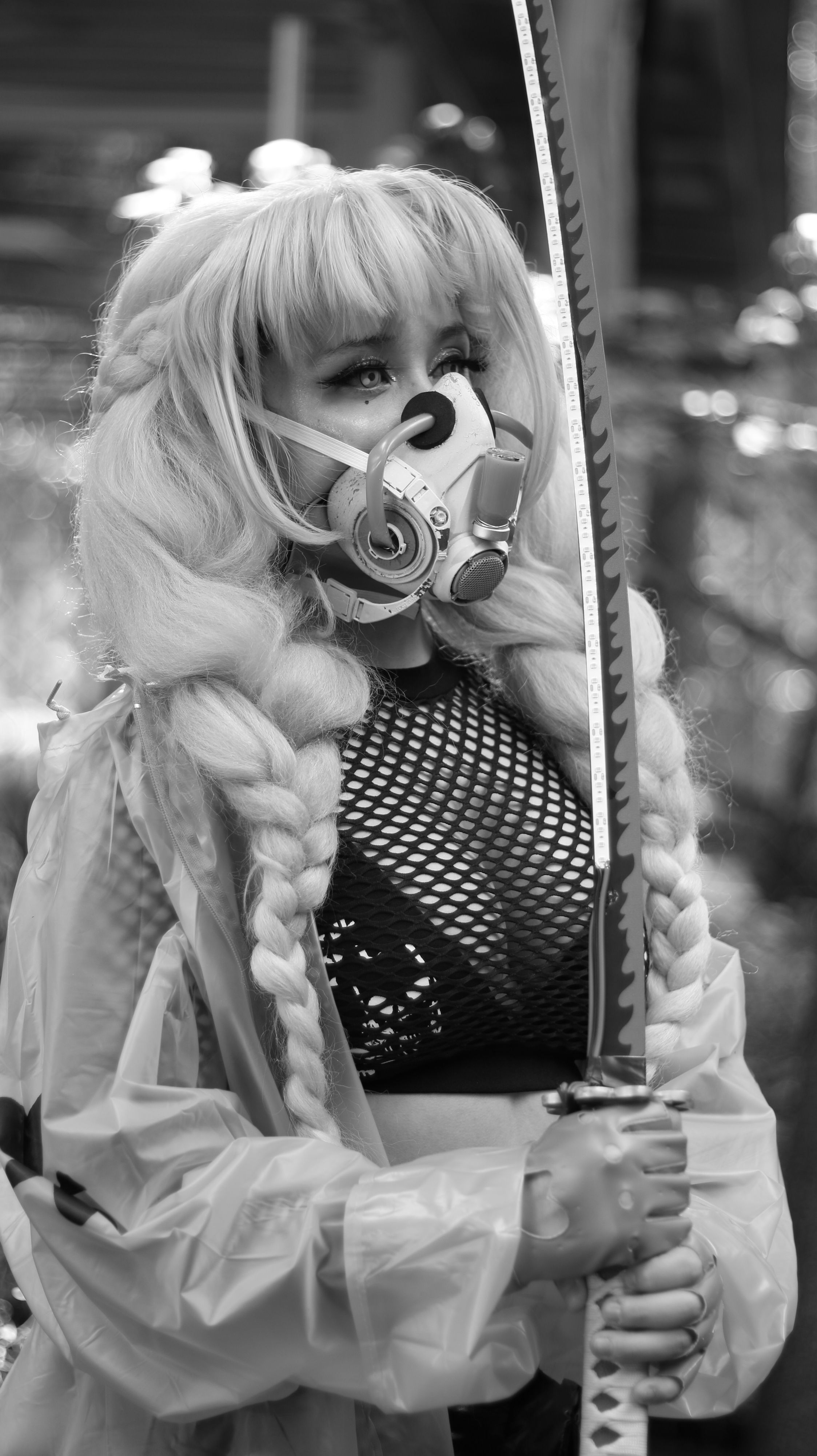 Black and white portrait of a woman holding a katana, wearing a gas mask and braided hair.