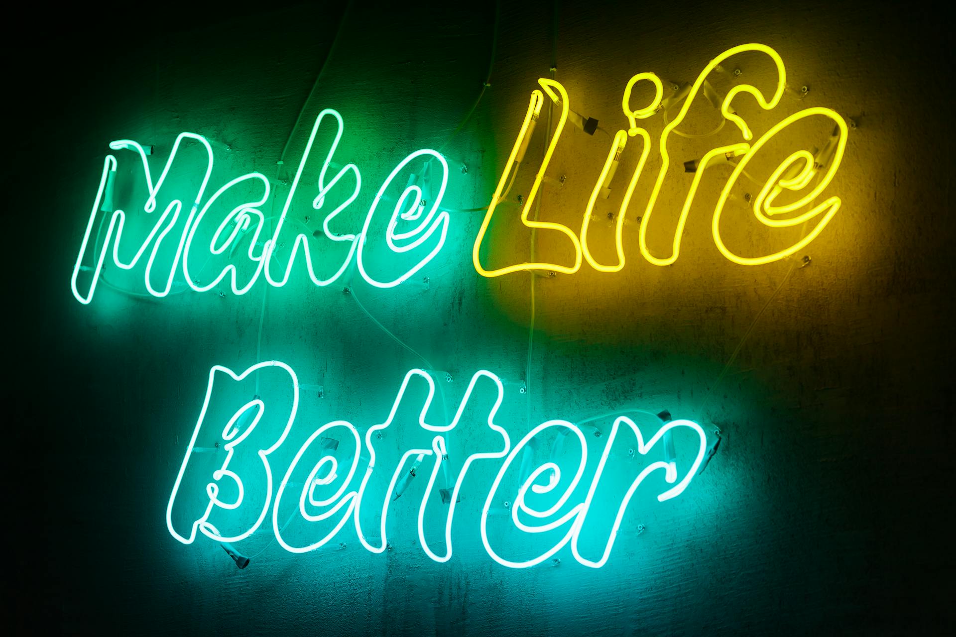 Vivid neon sign displaying the motivational message 'Make Life Better' in a colorful and eye-catching style.