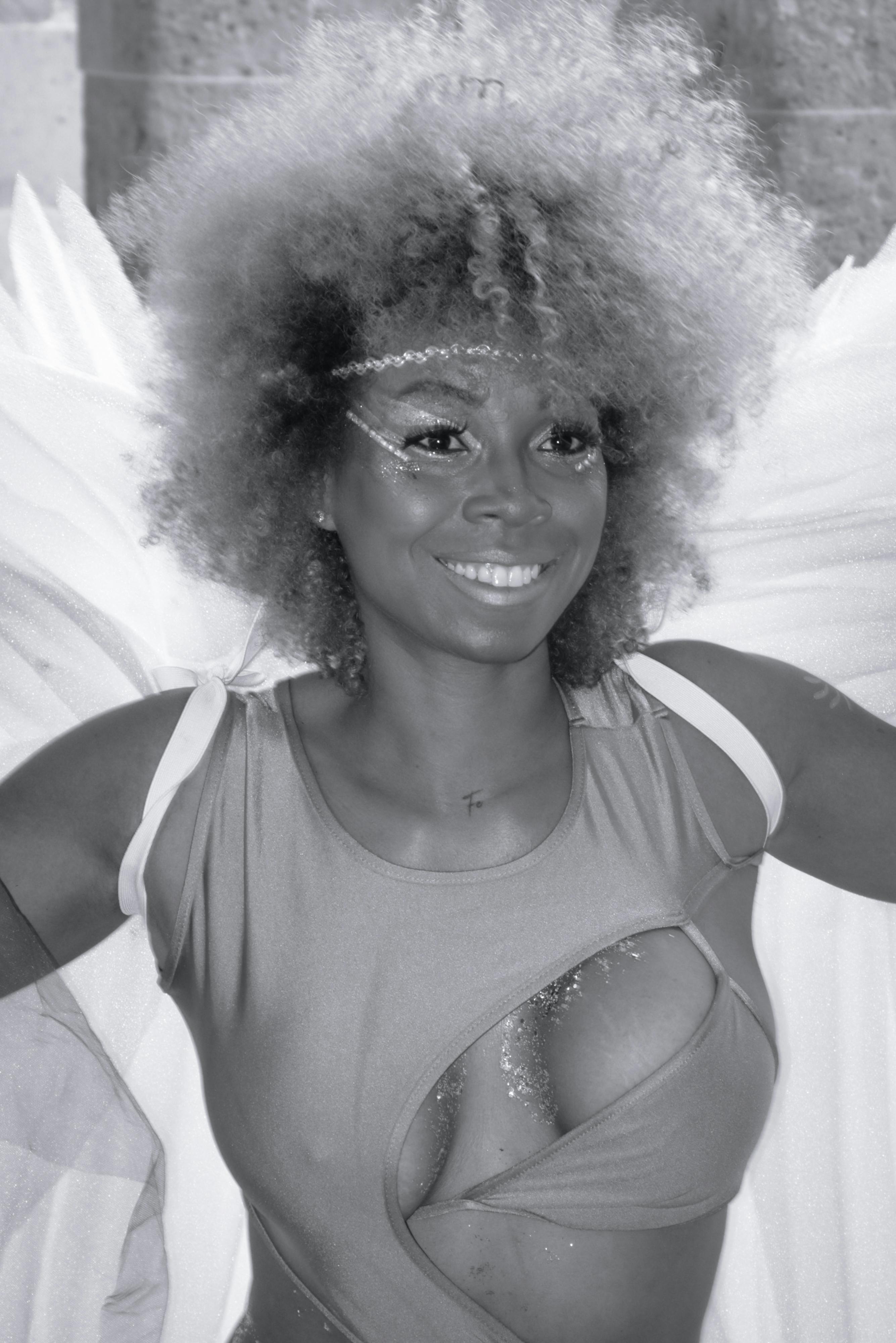 Kostenlos Eine fröhliche Frau mit Afrofrisur, die ein Engelskostüm in Schwarz und Weiß trägt. Stock-Foto