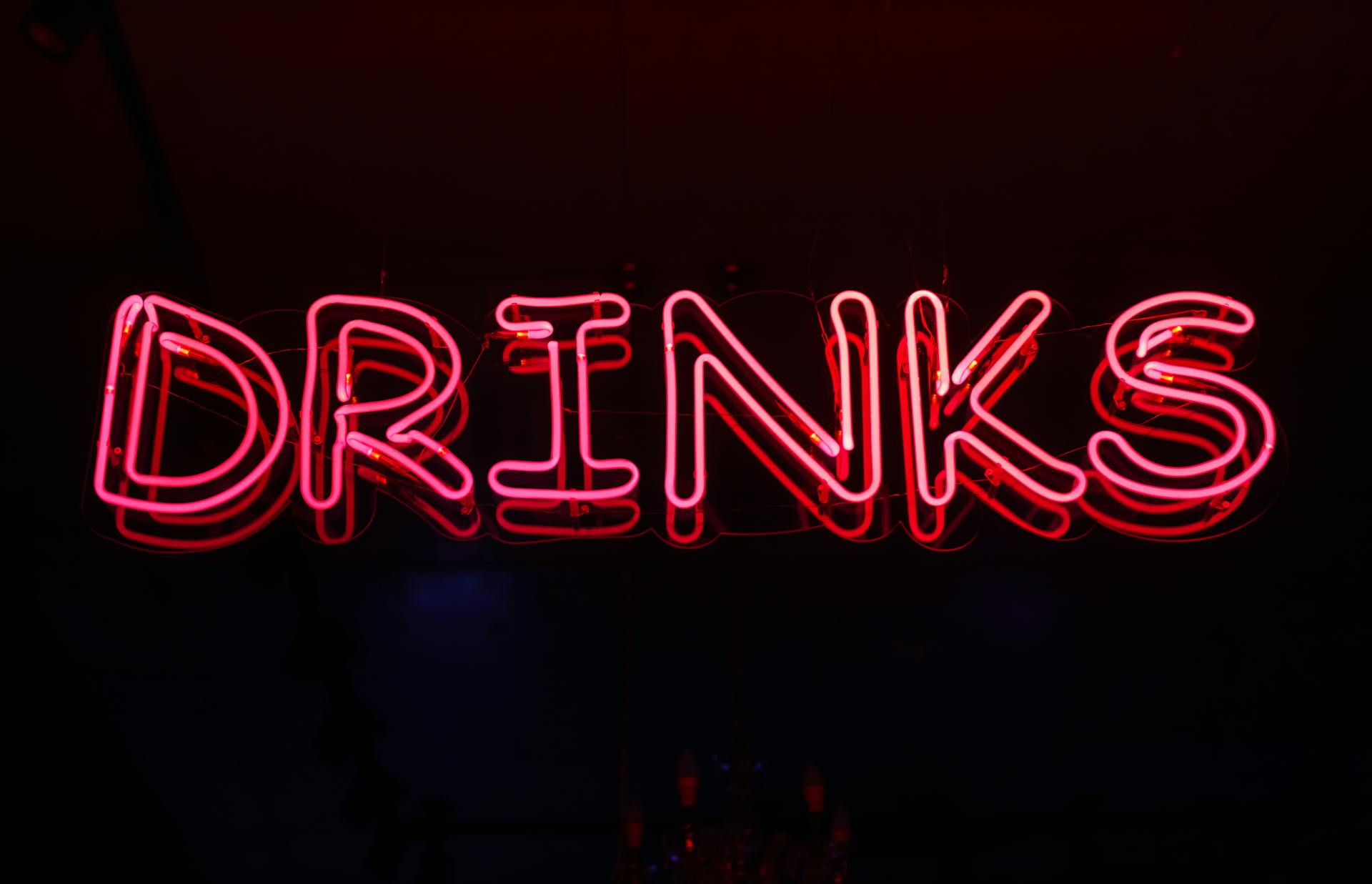 Eye-catching neon 'drinks' sign glowing brightly against a dark background.