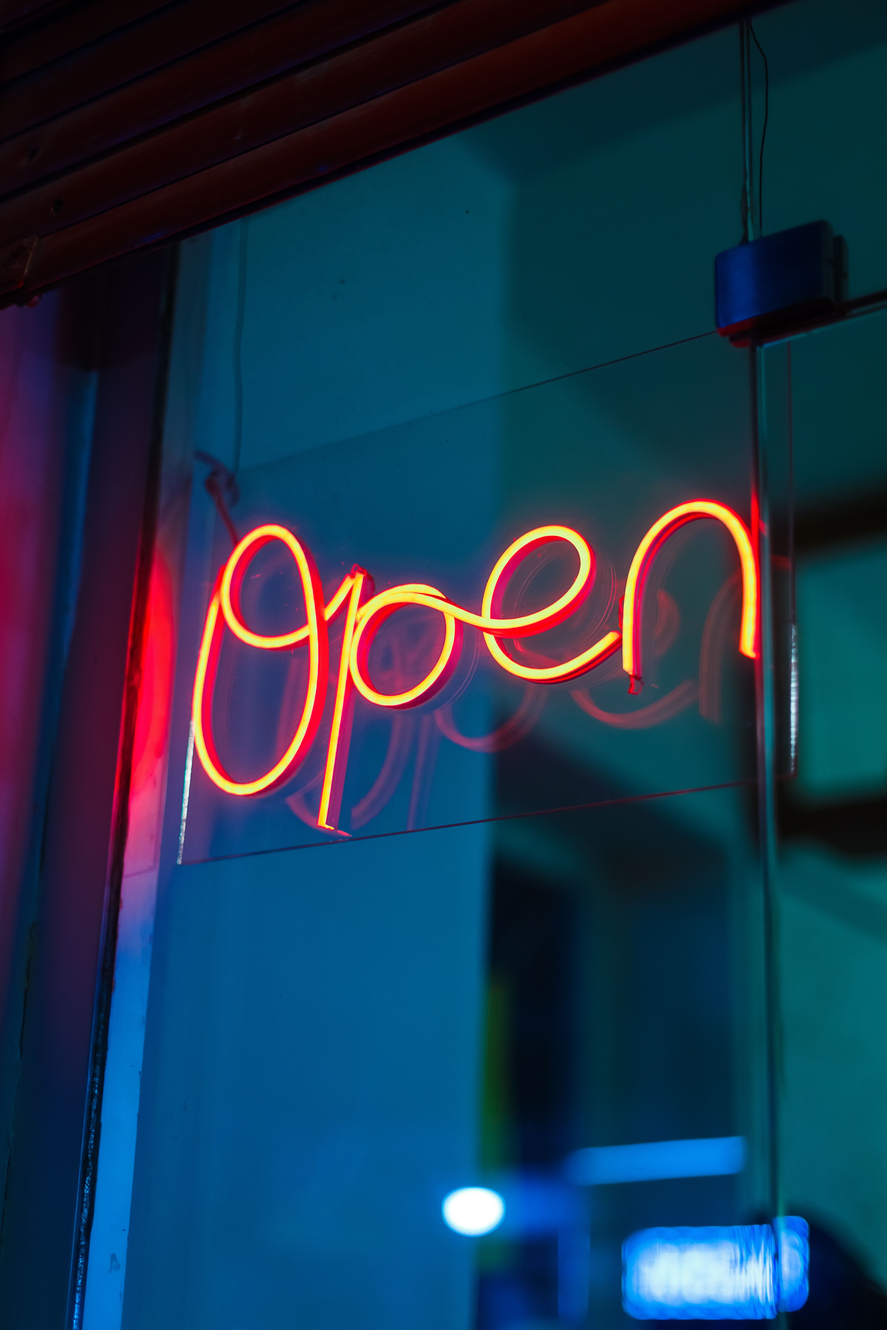 A glowing neon open sign brightens up the night with its vivid red hue.