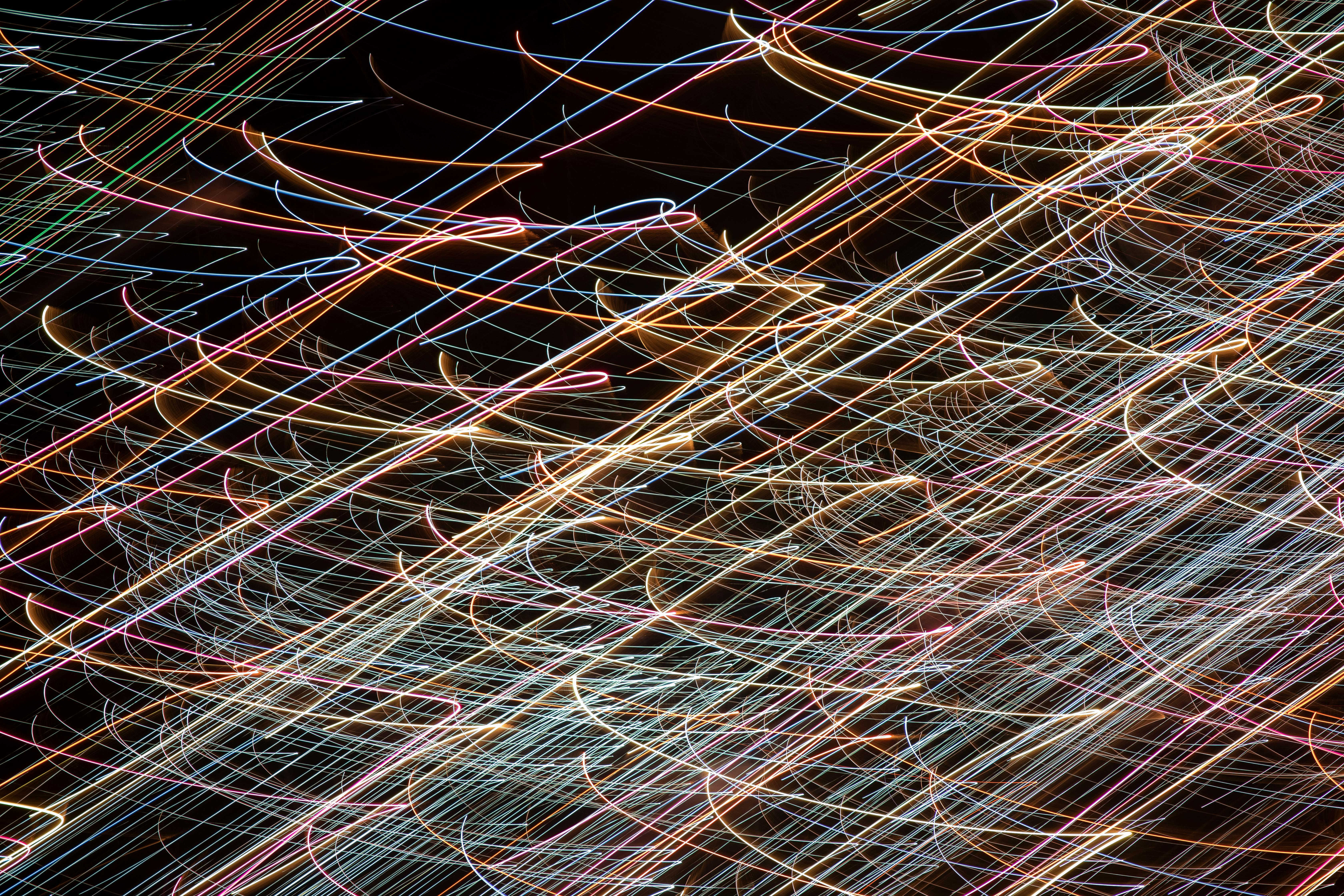 Gratis Dynamisk abstrakt billede, der viser farverige lyse striber mod en mørk baggrund, og fanger bevægelse. Lagerfoto