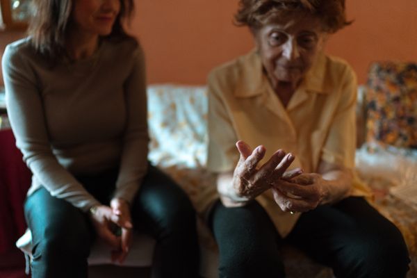 Adult daughter sitting beside her elderly mother at home while talking about moving a parent into assisted living