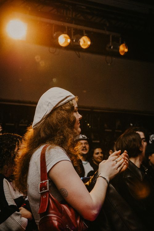 Free A young woman claps and enjoys a live concert in Berlin, Germany with vibrant stage lighting. Stock Photo